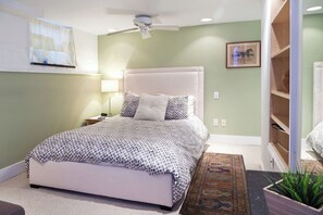 A bedroom with a bed, a nightstand, a lamp, a ceiling fan, a rug, and a wall-mounted shelf. - Downtown Large Apartment Guest Suite (Washington)
