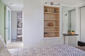 Une chambre à coucher comprenant un lit, une étagère intégrée agrémentée d’objets décoratifs, un radiateur et un miroir.
