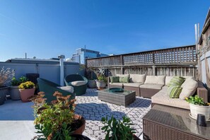 Une terrasse sur le toit, aménagée avec du mobilier d’extérieur, des plantes en pot et offrant une vue sur le panorama urbain.