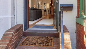Een entree met een pad van baksteen dat leidt naar een modern interieur.