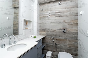 A modern bathroom with a marble sink, a large mirror, and a shower with a wooden wall backdrop. - Wish Copacabana - Praia (Rio de Janeiro)