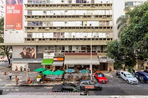 A multi-story building with a ground-level café, outdoor seating, and a visible storefront. - Wish Copacabana - Praia (Rio de Janeiro)