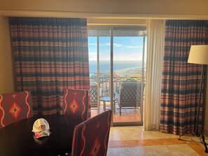 Ein Zimmer mit Esstisch, Stühlen, einer Lampe und Blick auf den Ozean durch eine Schiebetür.