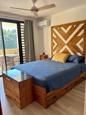 Un dormitorio con cama, cabecero de madera, mesita de noche y vistas al exterior.