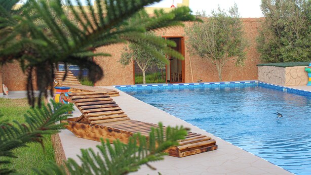 Una piscina con tumbonas de madera y una pared de piedra.