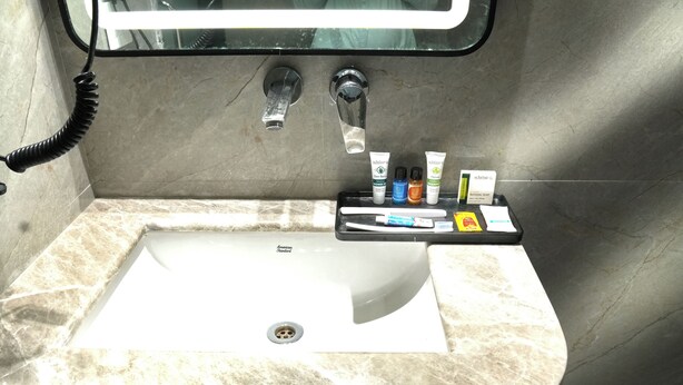 A bathroom with a marble sink, a mirror, and toiletries on a tray. - Hotel Mountain Bliss new delhi  (New Delhi)