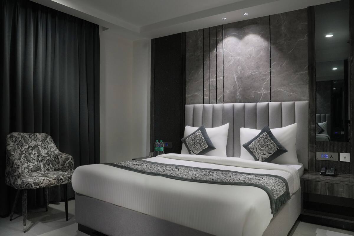 Una camera da letto moderna con un letto grande, una sedia e un comodino con un telefono.
