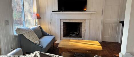A cozy living room with a fireplace, a television mounted above it, a sofa, and a coffee table.