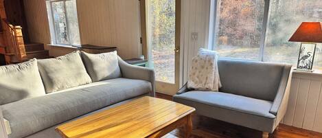 A cozy living room with a wooden coffee table, a grey sofa, and a blue armchair.