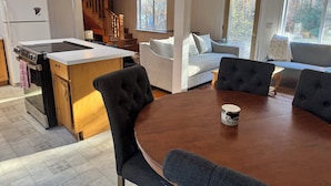 Una cocina moderna con una isla central, un comedor con mesa de madera y una sala de estar con sofá y ventana.