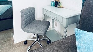 Quarto com escrivaninha, cadeira, cama e quadro na parede.