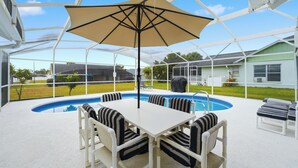 An outdoor pool area with a covered seating area, a pool table, and lounge chairs. - Disney Marvelous 4-bedroom house with a pool (Kissimmee)