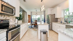 A modern kitchen with stainless steel appliances, white cabinetry, and a central island. - Luxurious 6-bedroom house with pool, grand piano and massage chair in Houston (Houston)