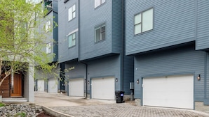 En moderne, fleretagers boligbygning med ensartet facade, flere garageporte og en asfalteret indkørsel.
