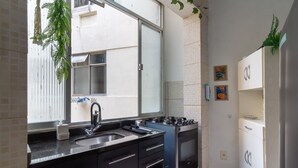 Une cuisine avec une fenêtre, un évier, une cuisinière et des placards.