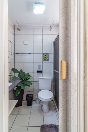 Een compacte, schone badkamer met toilet, wastafel en een plant.