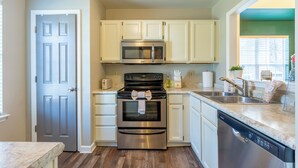 A modern kitchen with white cabinets, stainless steel appliances, and a dishwasher. - Stylish Durham Retreat • 3BR, Private Backyard • Near NCCU, Duke & Downtown (Durham)