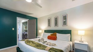 A bedroom with a bed, green walls, a white ceiling fan, and a nightstand with a lamp. - Stylish Durham Retreat • 3BR, Private Backyard • Near NCCU, Duke & Downtown (Durham)