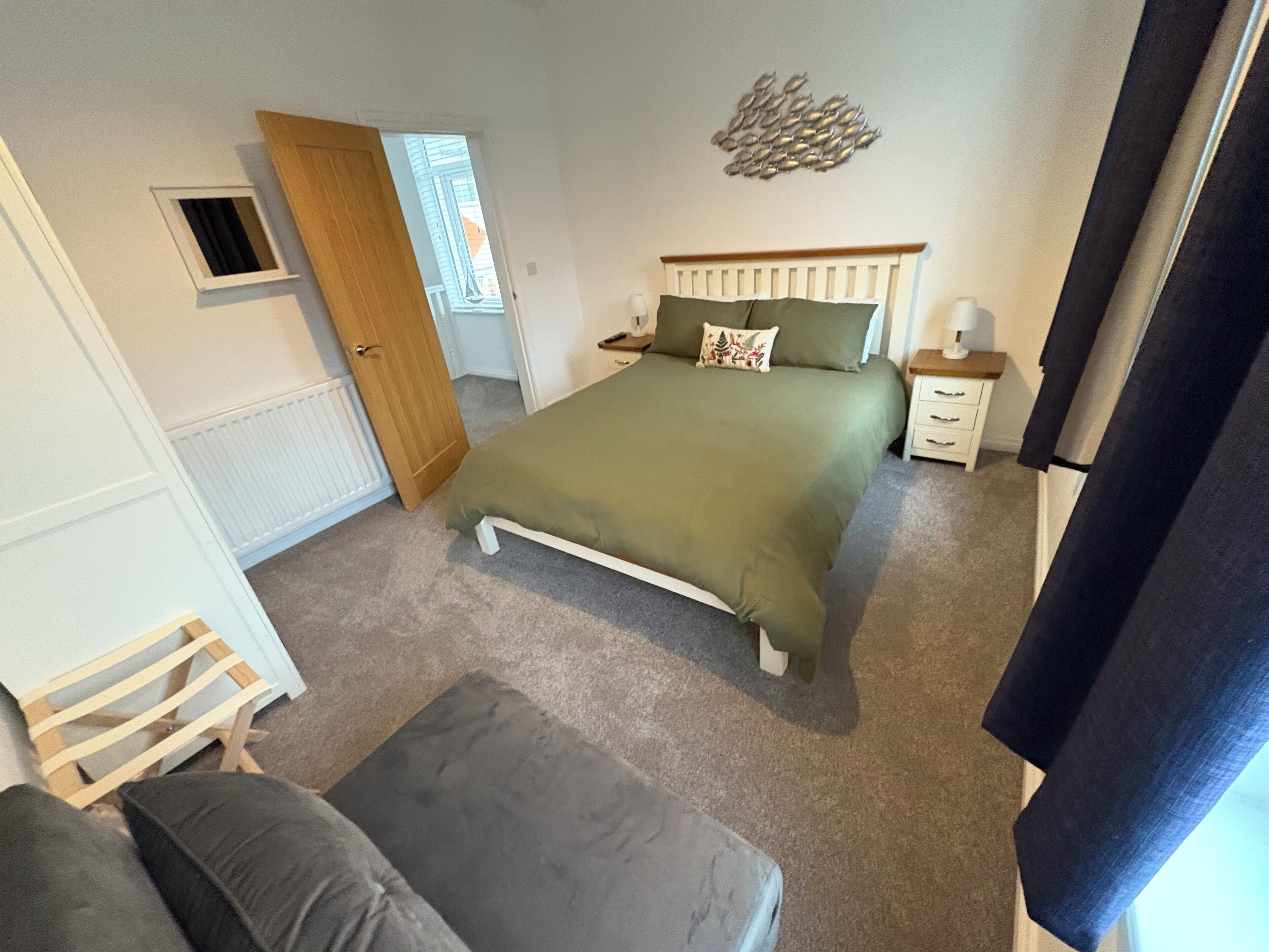 Een slaapkamer met een bed, nachtkastje, dressoir, raam en deur.