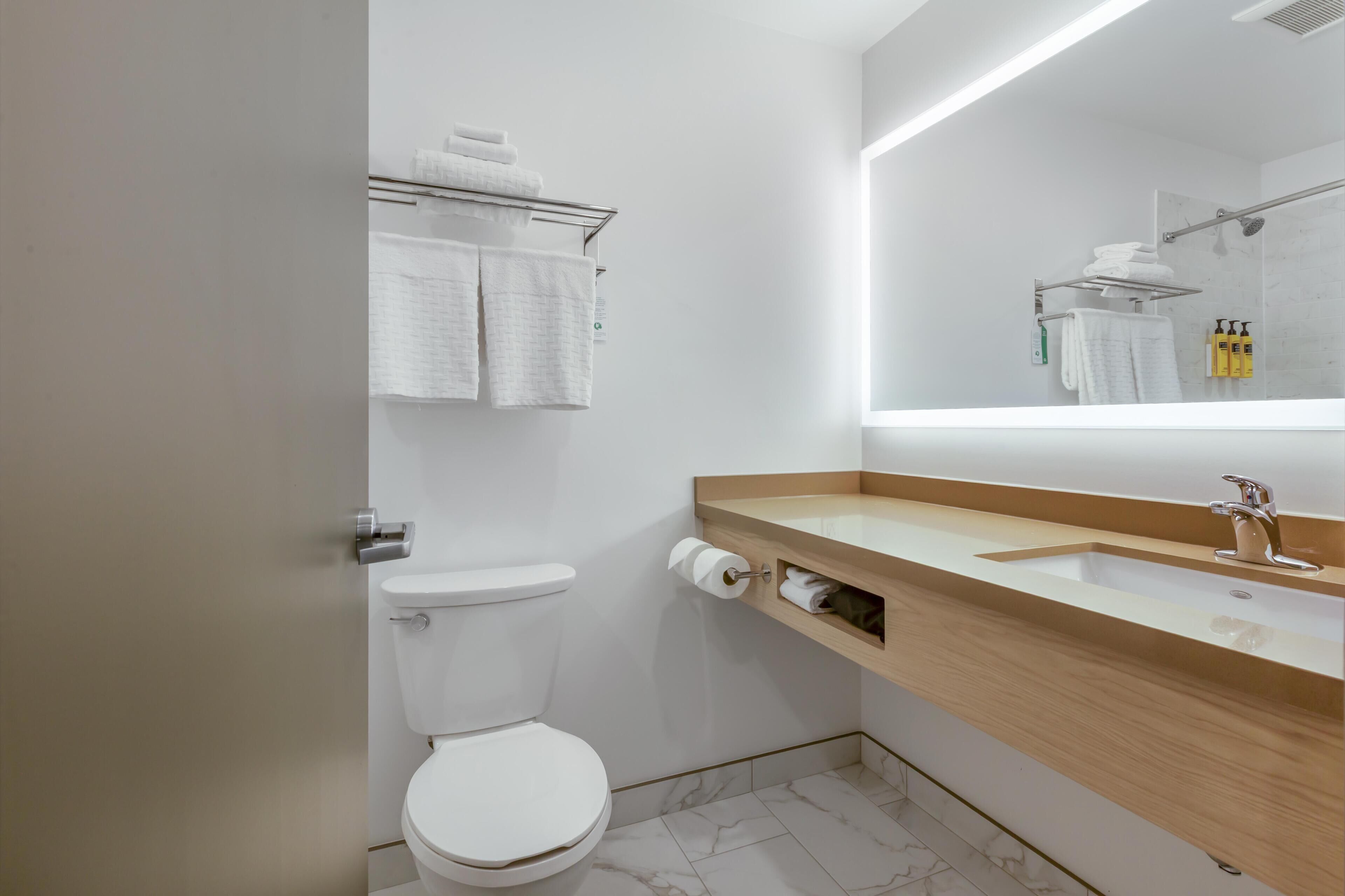 Ein modernes Badezimmer mit Toilette, Waschbecken, Spiegel und Handtuchhalter.