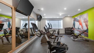 A gym with cardio machines, a mirror, and a window.