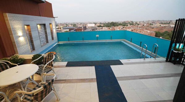 A rooftop swimming pool with a view of the cityscape.