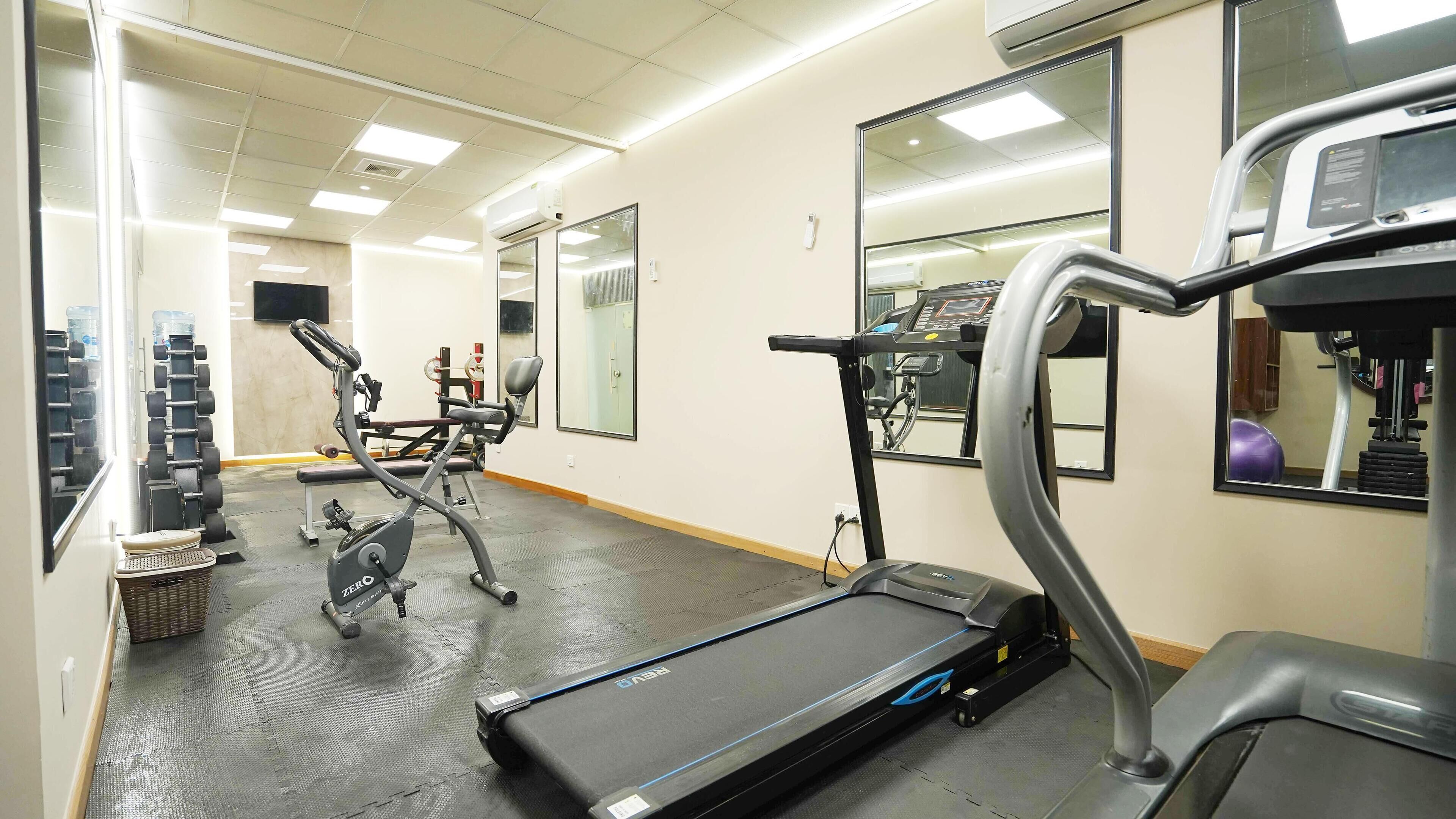 A gym with exercise equipment, including a treadmill, elliptical, and weight machines.