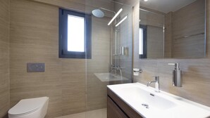 A modern bathroom with a toilet, a sink, a shower, and a large mirror.