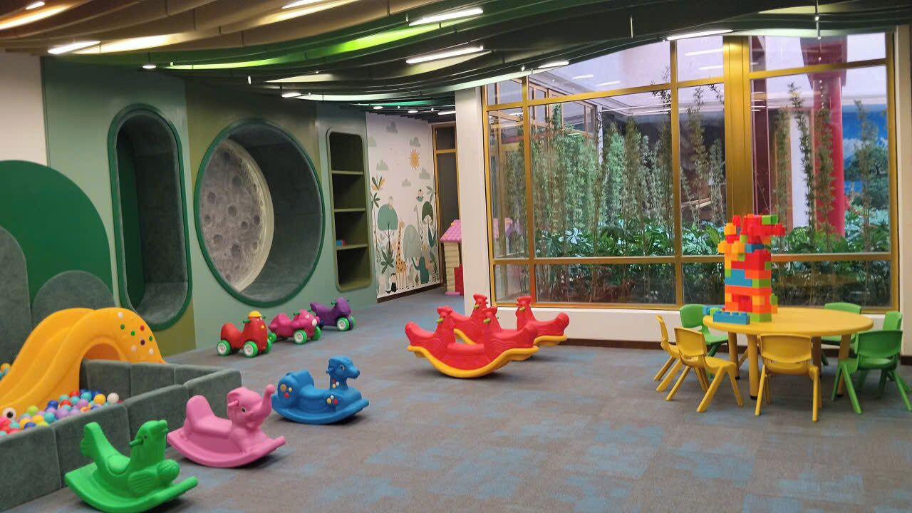 A children's play area with a slide, rocking horses, and a table with chairs.