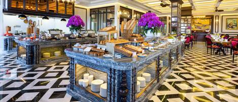 A hotel lobby with marble counters, chandeliers, and a checkered floor.