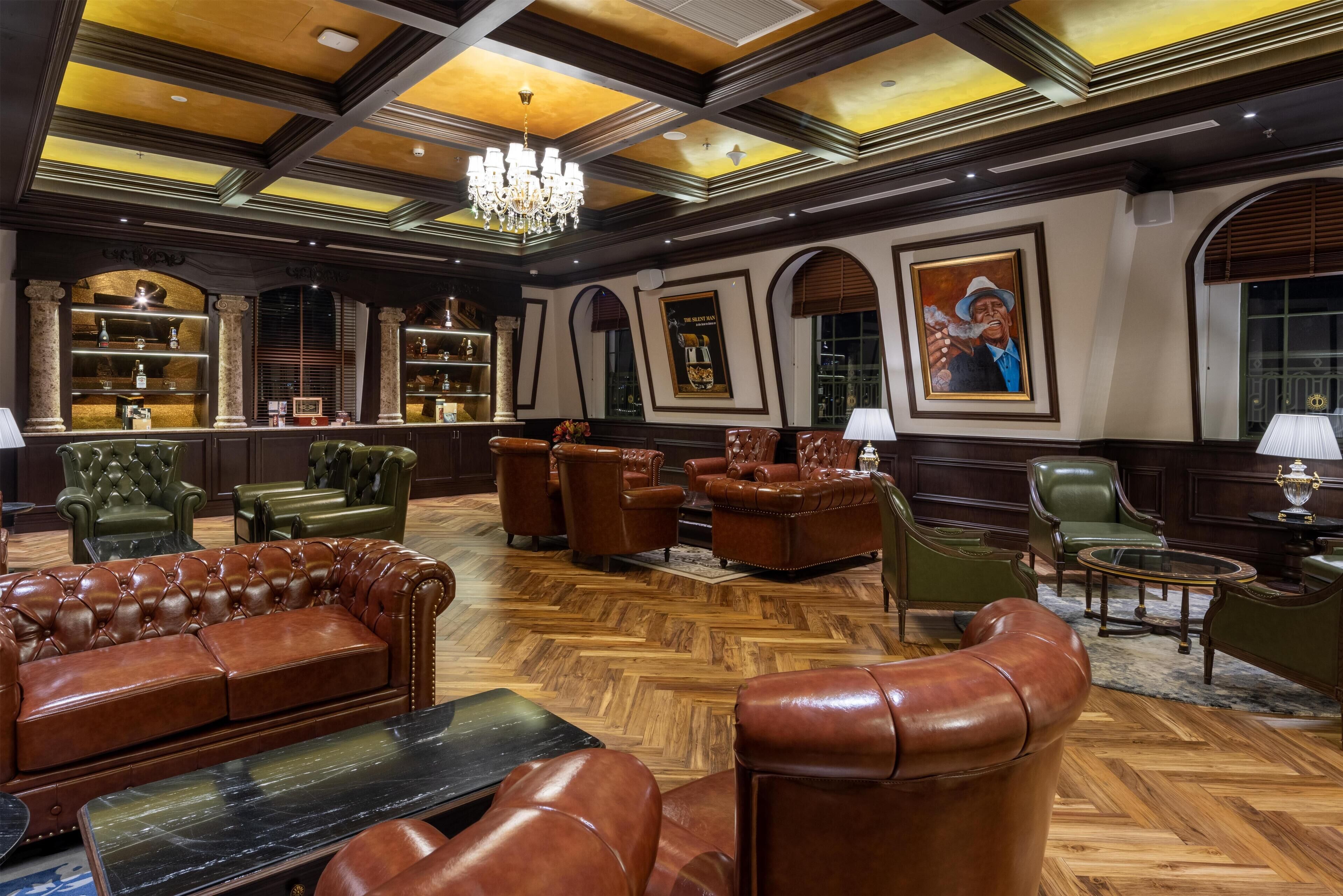 A luxurious lobby with leather sofas, a chandelier, and wooden flooring.