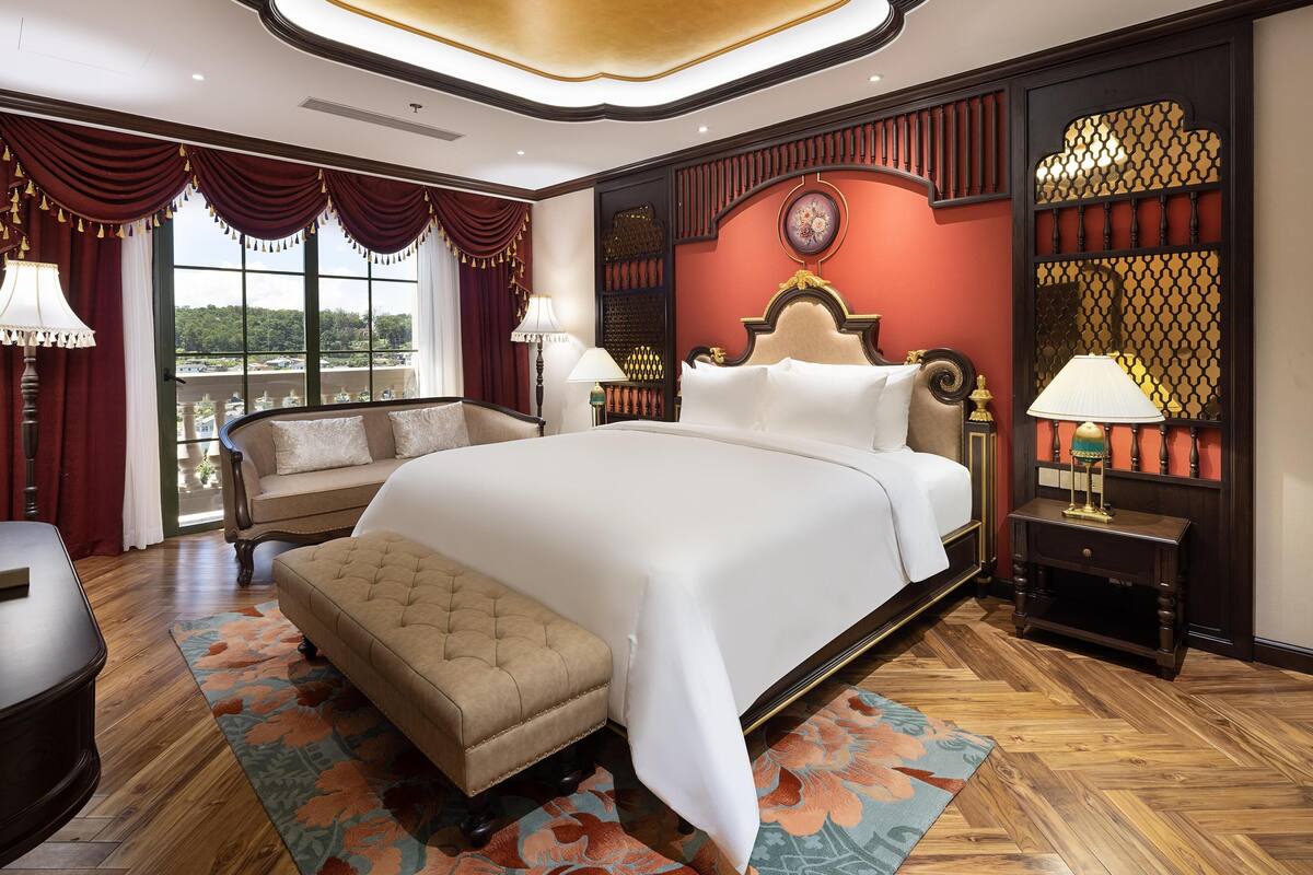 A spacious bedroom with a large bed, a sitting area, and a view of the outdoors.