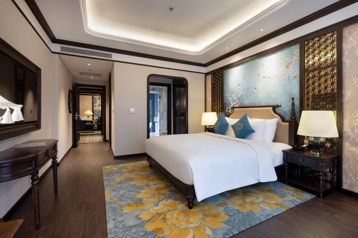 A hotel room with a large bed, a desk, a chair, and a decorative wall.
