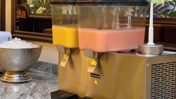 A juice dispenser with two containers, a bowl of ice, and a decorative mural in the background.