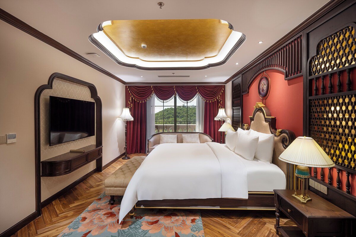 Une chambre spacieuse avec un grand lit, un téléviseur à écran plat fixé au mur et un panneau décoratif mural.