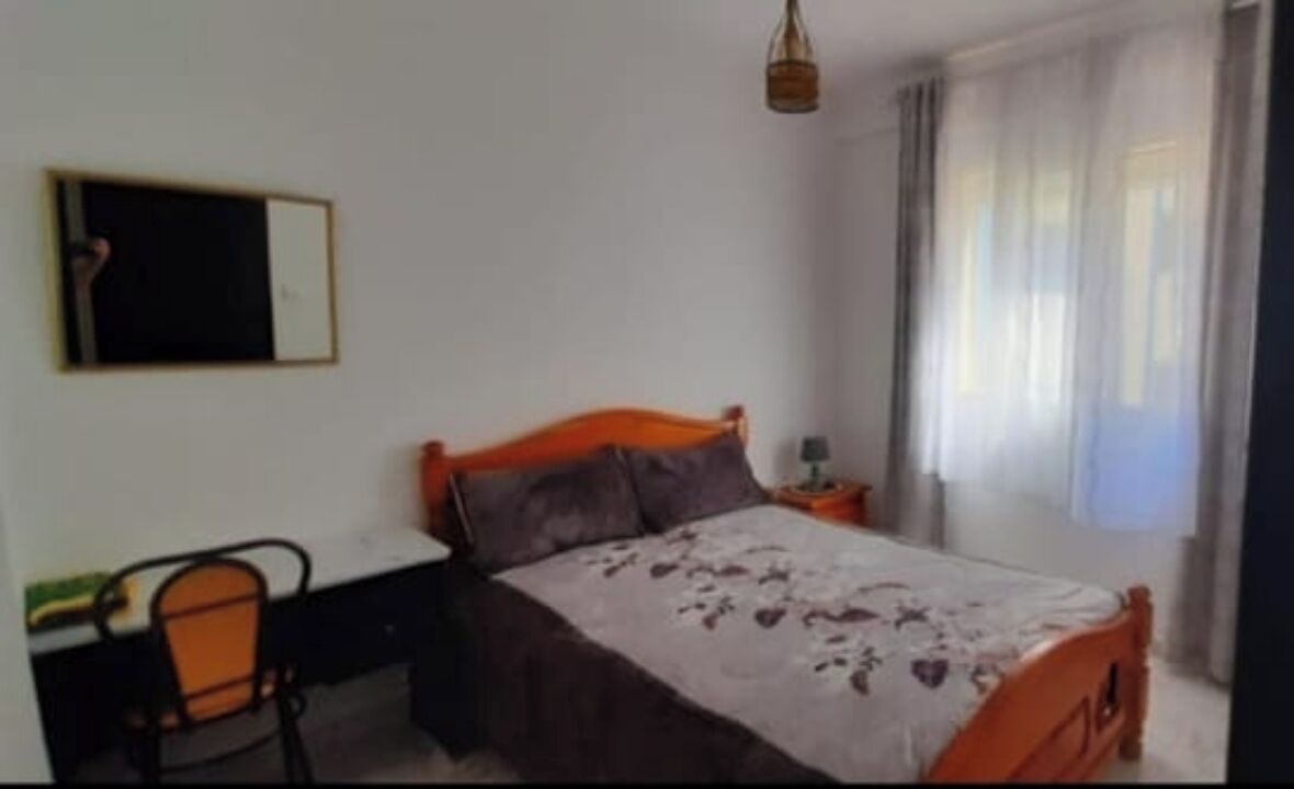 Un dormitorio con cama, escritorio y silla.