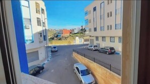 A view from a window overlooking a street with parked cars and buildings. - Tŕés own apartment located in catiér calabonita 5 min from the bus station (Al Hoceïma)