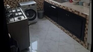 A compact kitchen with a gas stove, washing machine, tiled backsplash, and a window with blinds. - Tŕés own apartment located in catiér calabonita 5 min from the bus station (Al Hoceïma)