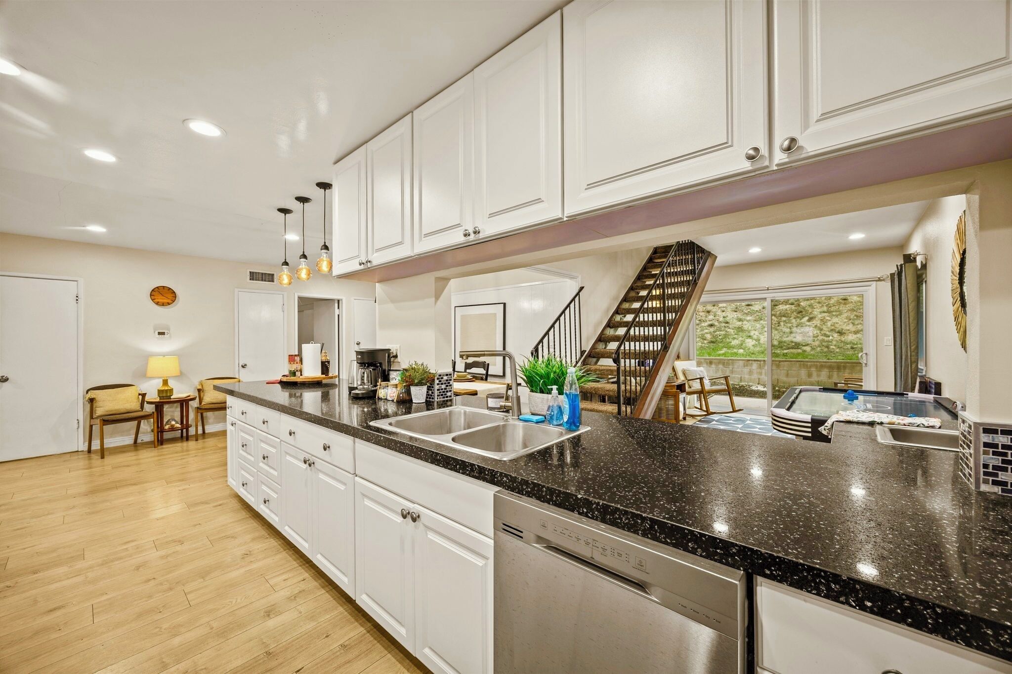 A modern kitchen with white cabinetry, granite countertops, a dishwasher, and a built-in stove.