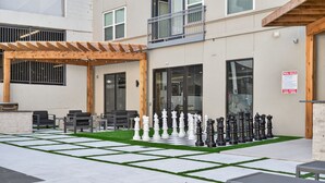 An outdoor seating area with chess pieces, a pergola, and a pool rules sign. - Worldcup Ready Stylish 1BR in West Village  Pool + Free Parking (Dallas)