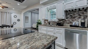 Una cocina moderna con armarios blancos, encimera de granito y lavavajillas de acero inoxidable.