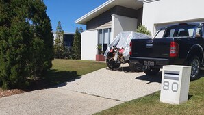 Un camino de entrada que lleva a una casa moderna con una camioneta estacionada y una motocicleta.