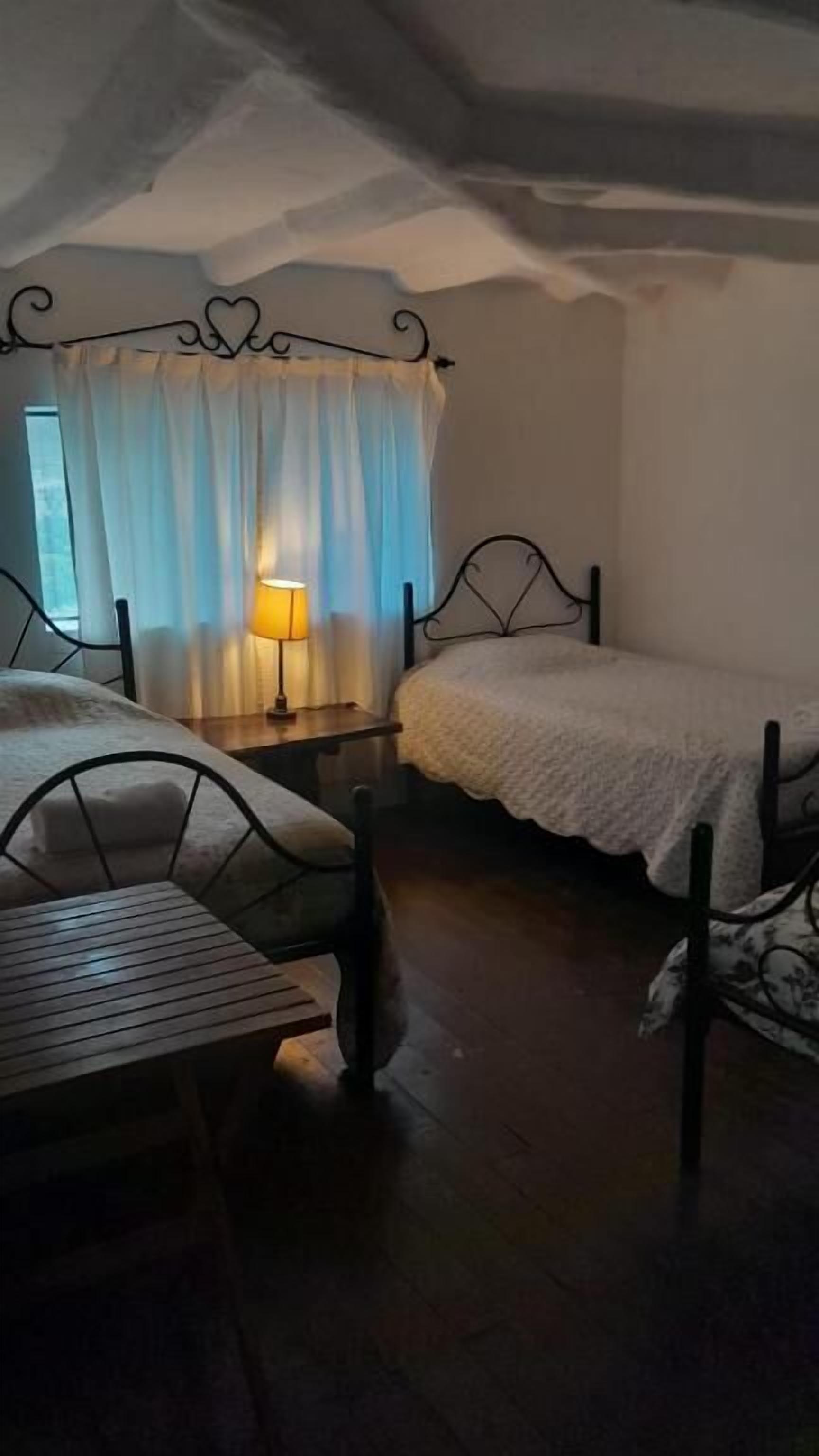 Un dormitorio con dos camas individuales, una mesa de madera y una lámpara.