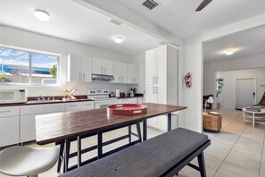 Une cuisine moderne avec des meubles blancs, une table à manger en bois et un banc.
