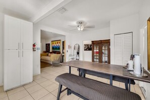 A kitchen with a dining table, bench, white cabinets, and a ceiling fan. - Suarez Art Stay, Buena Vista, Sleeps 10, Park (Miami)