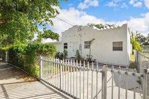 A white building with a gated entrance, surrounded by greenery. - Suarez Art Stay, Buena Vista, Sleeps 10, Park (Miami)