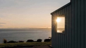 A coastal view from a building with a window overlooking the sea. - Couples Luxury Retreat with Ocean Views and Outdoor Bath (Penguin)
