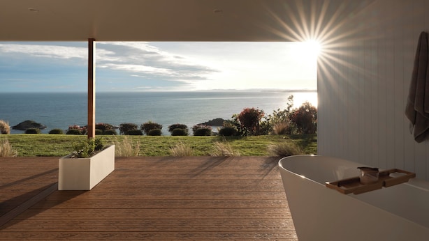 A modern bathroom with a large bathtub, a wooden deck, and a view of the ocean. - Couples Luxury Retreat with Ocean Views and Outdoor Bath (Penguin)