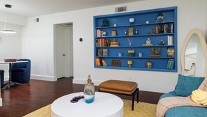 Un salon moderne avec une bibliothèque bleue, une table basse ronde blanche et un banc marron.