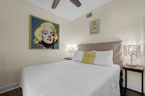 Une chambre d’hôtel avec un grand lit, une tête de lit, une table de chevet avec une lampe et un tableau encadré au mur.